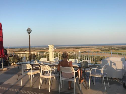 a woman sitting at a table on a balcony at Hotel Villa Sevasti in Katerini