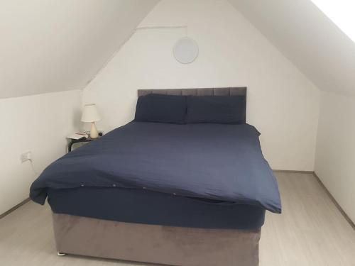 uma cama num quarto branco com um cobertor azul em Lavender lane cottage em Tralee