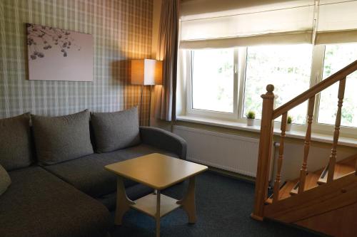 a living room with a couch and a table and a window at Nykščio Namai & SPA in Anykščiai