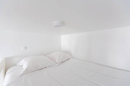 een wit bed met witte lakens en kussens bij Lavie Maison Bordeaux Bliss Studio in Bordeaux