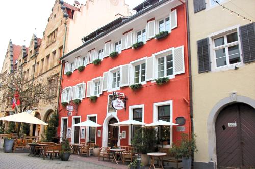 um edifício vermelho com mesas e guarda-sóis numa rua em Hotel am Fischmarkt em Constança