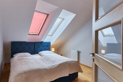 a bedroom with a bed with a blue headboard and windows at Apartamenty Świnoujście - Casa Marina in Świnoujście