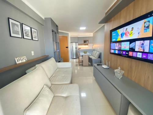 uma sala de estar com um sofá branco e uma televisão de ecrã plano em Luxuoso 2Q St Bueno - 3101 em Goiânia
