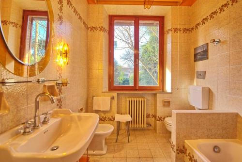 a bathroom with a sink and a toilet and a mirror at Villa Lauretana by PosarelliVillas in Torrita di Siena