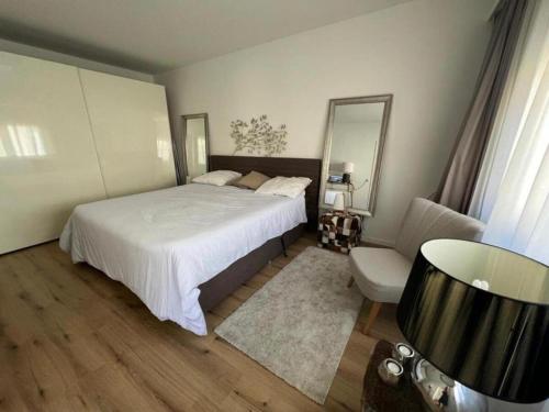 1 dormitorio con cama, silla y espejo en Stylish 1-bedroom condo close to exhibition square en Basilea