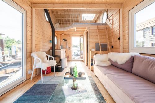 una sala de estar de una casa pequeña con sofá en Tolles Tiny-Hausboot GÜNTER mit Dachterrasse en Hamburgo