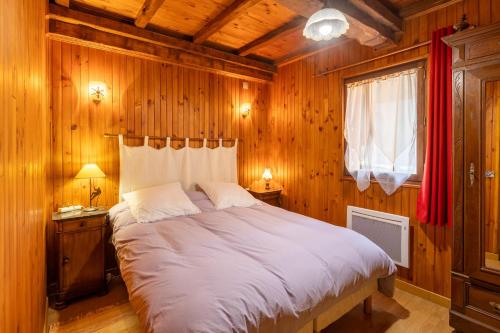 a bedroom with a large bed in a room with wooden walls at La Perle des Pyrénées - Maison pour 8 in Formiguères
