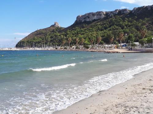 una spiaggia con persone in acqua e una montagna di CIMAROSA ROOM AFFITTI BREVI a Cagliari