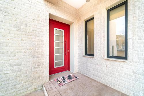 a red door on a white brick wall with a mat at The Mountain Villa in Aleimmatádes