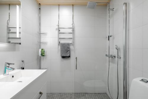 a white bathroom with a shower and a sink at Nice studio apartment on a pedestrian street in Helsinki