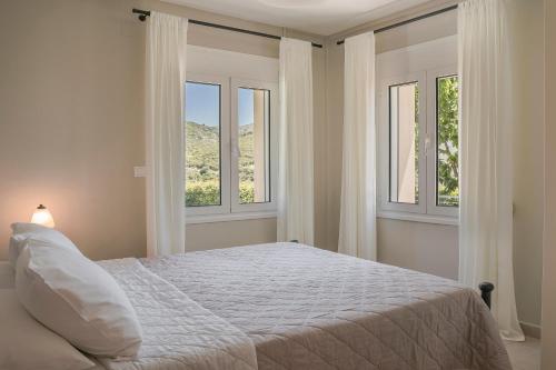 een witte slaapkamer met 2 ramen en een bed bij Sandy & Sofia in Kateliós