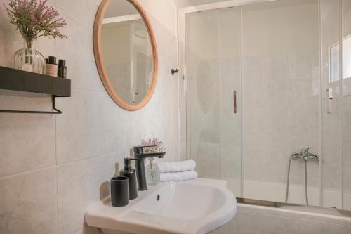 Baño blanco con lavabo y espejo en Sandy & Sofia, en Katelios