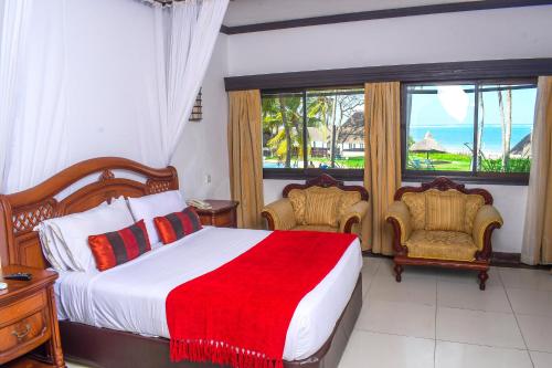 a bedroom with a bed and two chairs and a window at Cocoa Luxury Resort, Nyali, Mombasa in Mombasa
