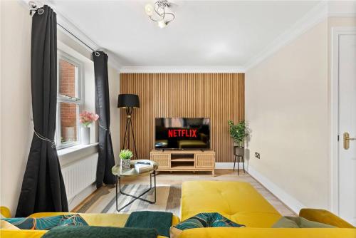 a living room with a yellow couch and a tv at Large 5 Bedroom House in the Cotswolds - Garden in Moreton in Marsh