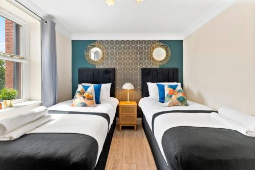 twee bedden in een kamer met zwart en wit bij Stunning 5 Bedroom House in the Cotswolds - Garden in Moreton in Marsh