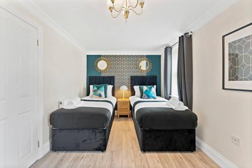 a room with two beds in a room with a chandelier at Large 5 Bedroom House in the Cotswolds - Garden in Moreton in Marsh