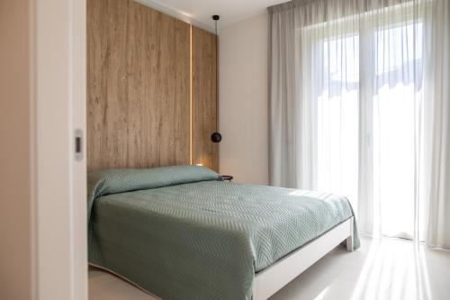 1 dormitorio con 1 cama con cabecero de madera y ventana en Viride Mare, en Numana