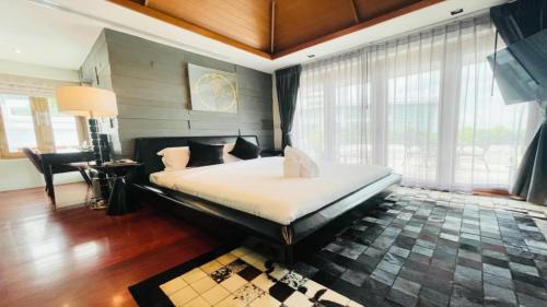 a bedroom with a large bed in a room with windows at Yizen Beachfront Seaview Villa in North Pattaya
