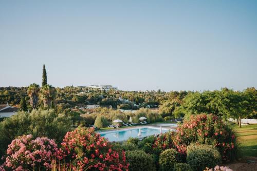 vistas a una piscina en un jardín con flores en Pelican Alvor en Alvor