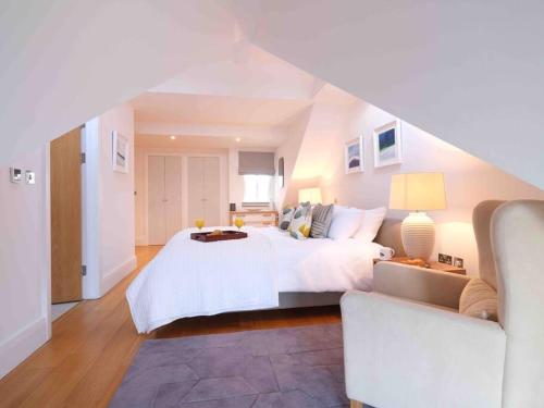 a large white bedroom with a bed and a couch at Luxurious apartment, 180° beach views & parking in St Ives