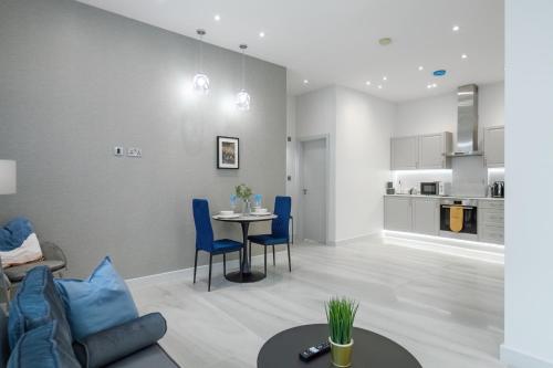 ein Wohnzimmer mit einem Tisch und blauen Stühlen in der Unterkunft LiveStay-Modern & Stylish Apartments in Didcot in Didcot