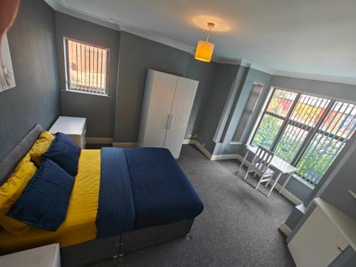 a bedroom with a bed with a yellow and blue blanket at Spacious large room 001 in Nottingham