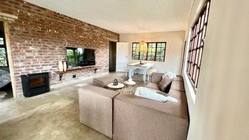 a living room with a couch and a brick wall at LoerieRoep Estate - Mountainview Accommodation Nelspruit in Nelspruit