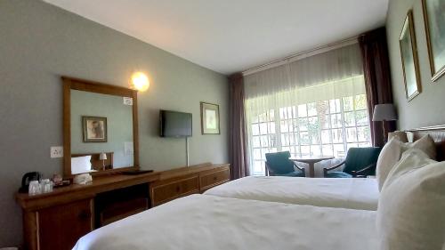 a hotel room with two beds and a desk and a window at Sundown Country Estate in Boshoek