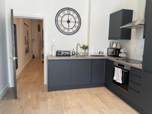 a kitchen with black cabinets and a clock on the wall at Luxury 2 bedroom Flat Sutton in Sutton