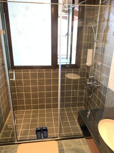La salle de bains est pourvue d'un lavabo et d'une douche avec deux chaussures. dans l'établissement Kinmen Happiness Shop, à Jinning