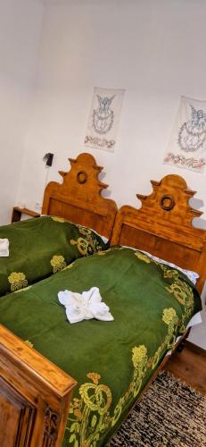 two beds with green sheets and white flowers on them at Dézsavár Vendégház in Majs