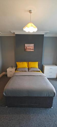 um quarto com uma cama grande e almofadas amarelas em Spacious double room 002 em Nottingham