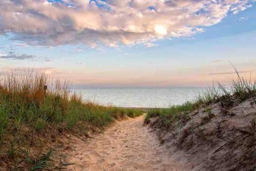 a dirt path leading to a beach with the ocean at Blue Birdhouse - Indiana Dunes - Pet Friendly in Chesterton