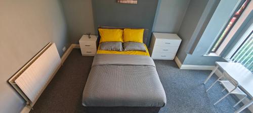 um pequeno quarto com uma cama com almofadas amarelas em Spacious double room 002 em Nottingham