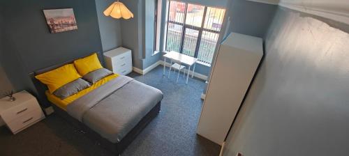 a bedroom with a bed with yellow pillows and a window at Spacious double room 002 in Nottingham