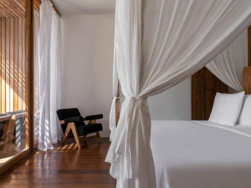 a bedroom with a white bed and a chair at KA BRU Beach Boutique Hotel in Barra Grande