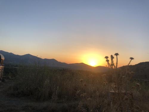 a sunset in a field with mountains in the background at Skapani's House in Mésa Lasithákion