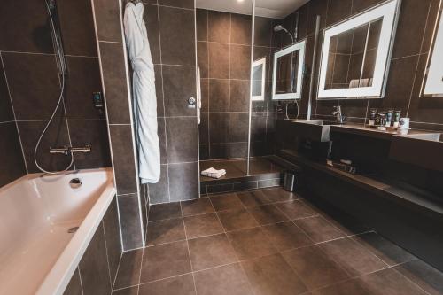 a bathroom with a shower and a tub and a sink at Novotel Toulouse Centre Wilson in Toulouse