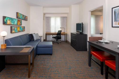 a living room with a blue couch and a tv at Residence Inn Port St Lucie in Port Saint Lucie