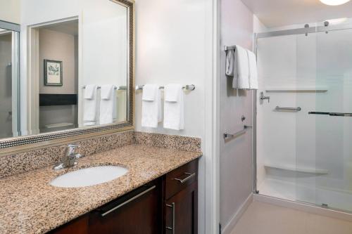 ein Bad mit einem Waschbecken und einer Dusche mit einem Spiegel in der Unterkunft Residence Inn Port St Lucie in Port Saint Lucie