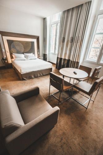 a hotel room with a bed and a table and chairs at Novotel Toulouse Centre Wilson in Toulouse