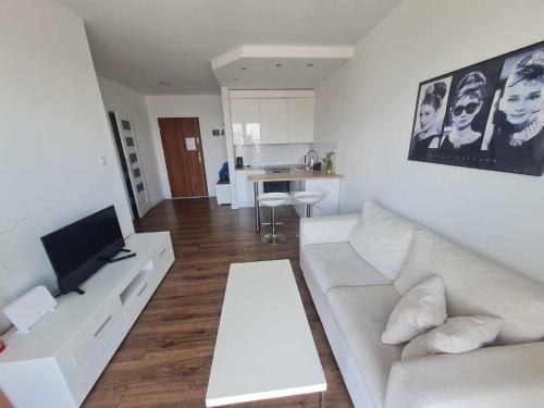 een woonkamer met een witte bank en een televisie bij Apartament Sunrise Poznań - Self Check-in 24h in Poznań