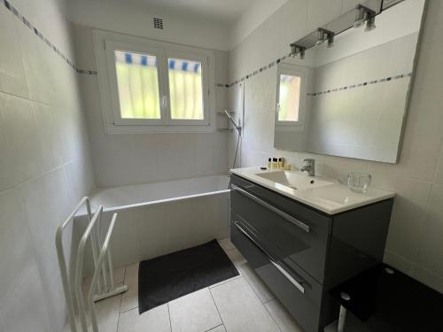 a bathroom with a tub and a sink and a mirror at La Villa Pavilou in Le Lavandou