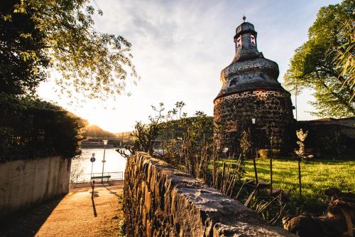 a stone wall with a tower next to a body of water at Gästehaus Korf in Unkel