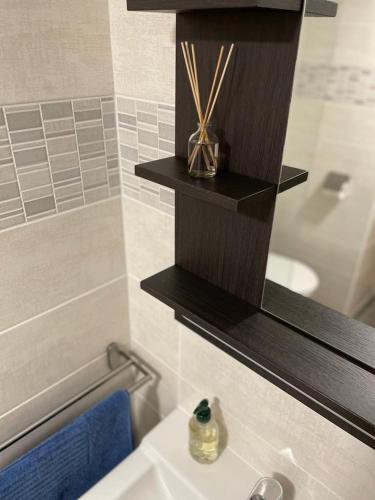 La salle de bains est pourvue d'un lavabo et d'une étagère au-dessus d'une baignoire. dans l'établissement Mas des Amarens, à Malaucène