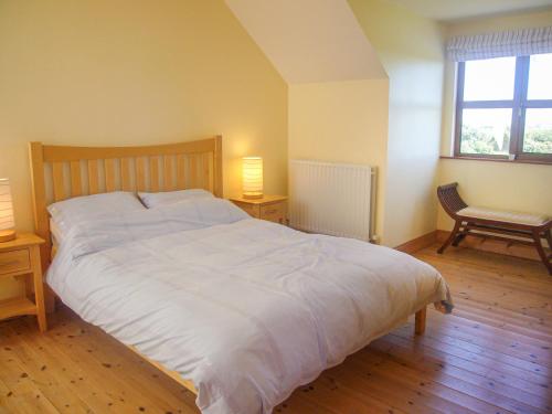 1 cama blanca grande en un dormitorio con 2 lámparas en Tra Gheal en Kilmore Quay