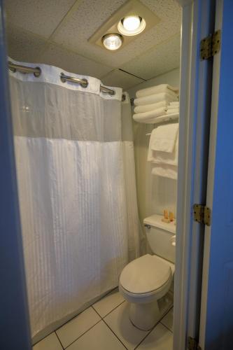a bathroom with a white shower curtain and a toilet at The White Sands Resort and Spa in Point Pleasant Beach