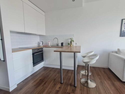 a kitchen with white cabinets and a table and stools at Apartament Sunrise Poznań - Self Check-in 24h in Poznań