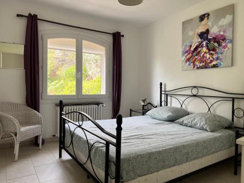 a bedroom with a black bed and a window at La Villa Pavilou in Le Lavandou