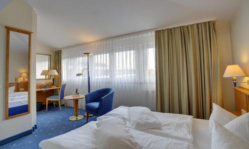 Habitación de hotel con cama y escritorio en ACHAT Hotel Magdeburg en Magdeburgo